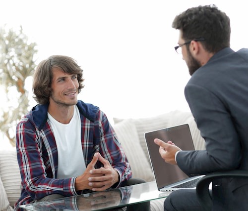 deux hommes discutant devant une table basse